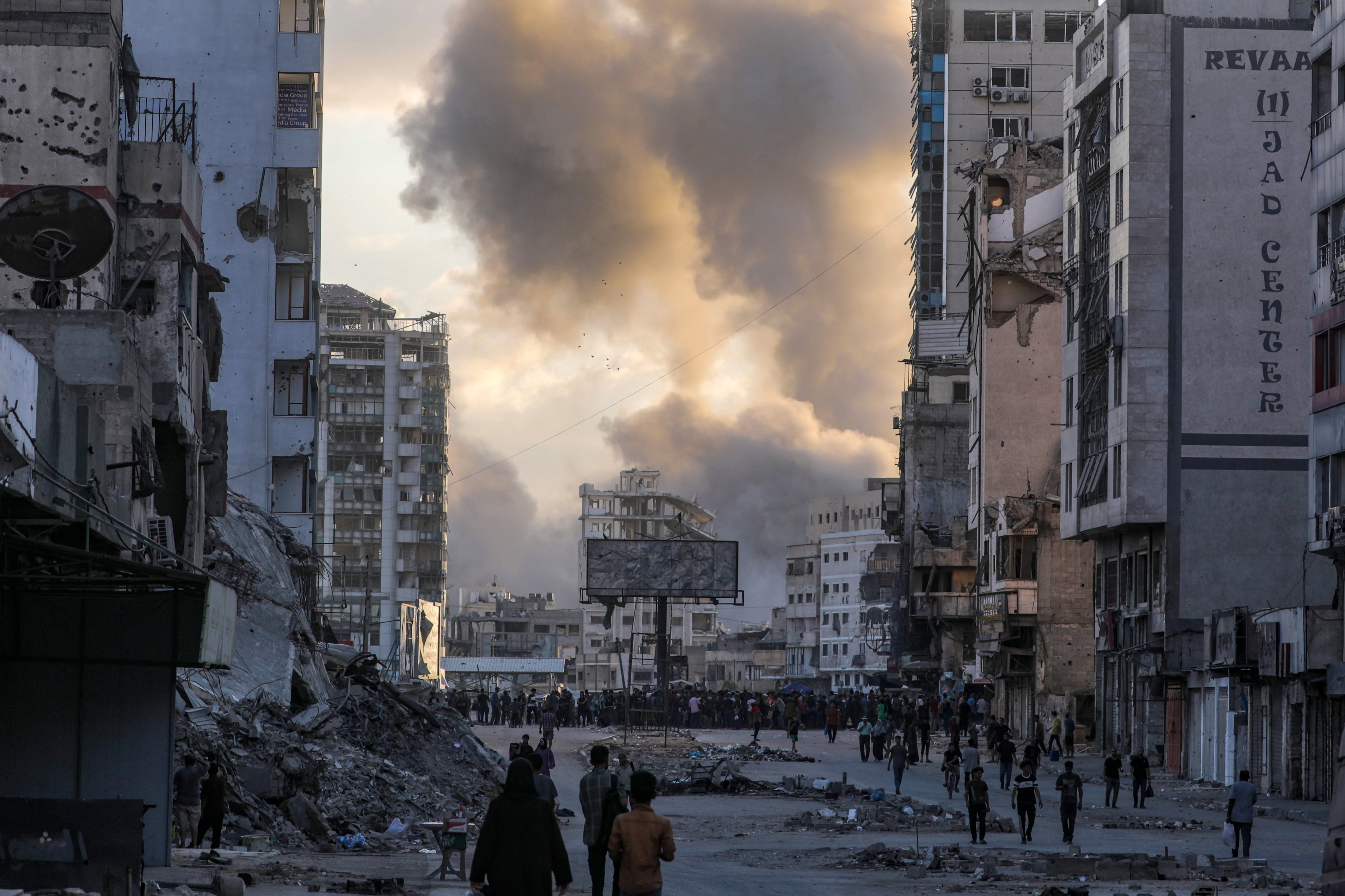 Palestinos se movilizan a la plaza Al Saraya mientras se eleva el humo tras un ataque aéreo israelí en la ciudad de Gaza
