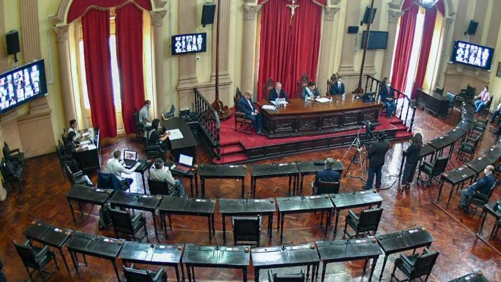 Recinto semi vacío y las pantallas que muestran a los legisladores conectados