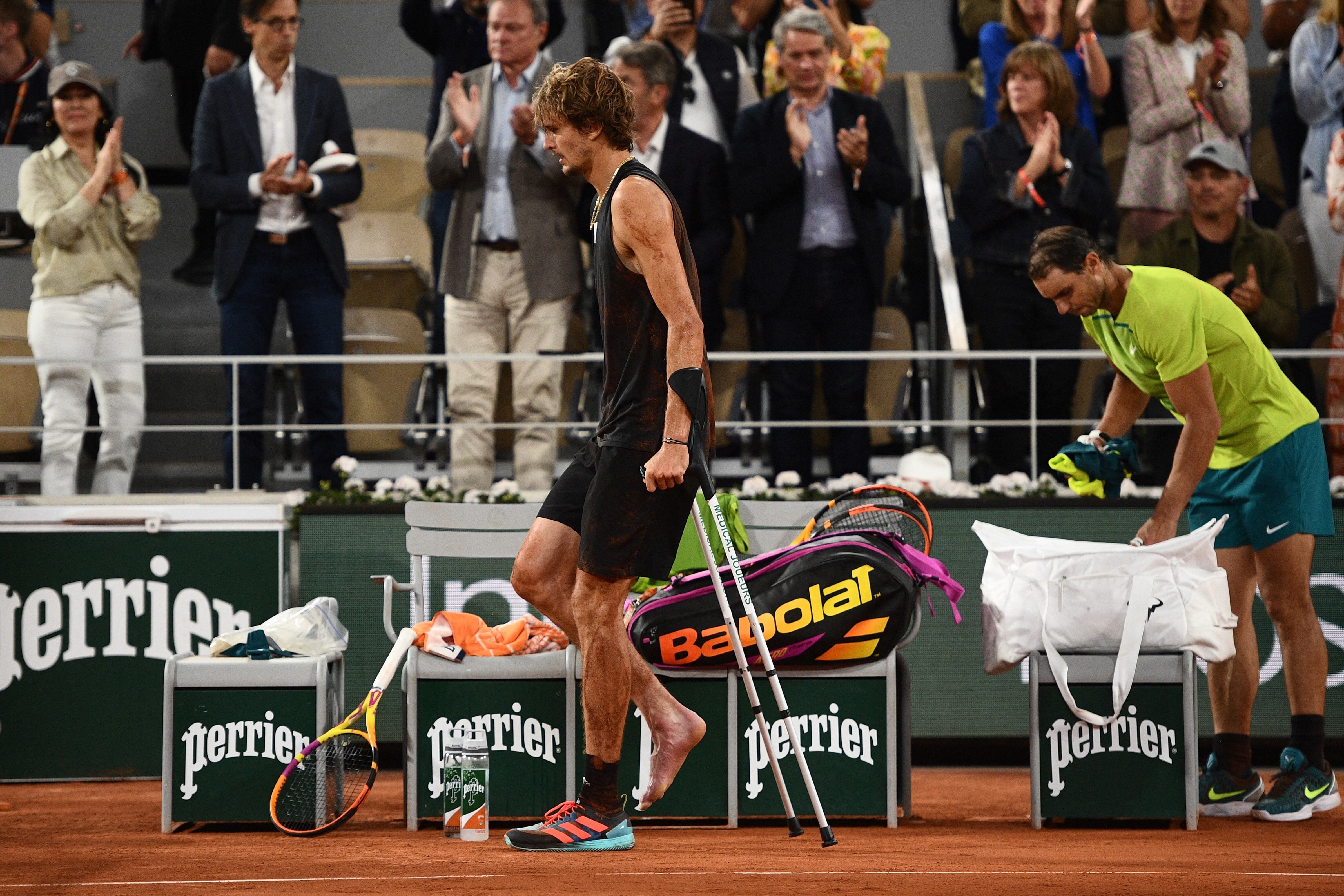 Zverev, retirándose con dolor y en muletas, frente a la mirada de Nadal y el público (Foto: AFP).