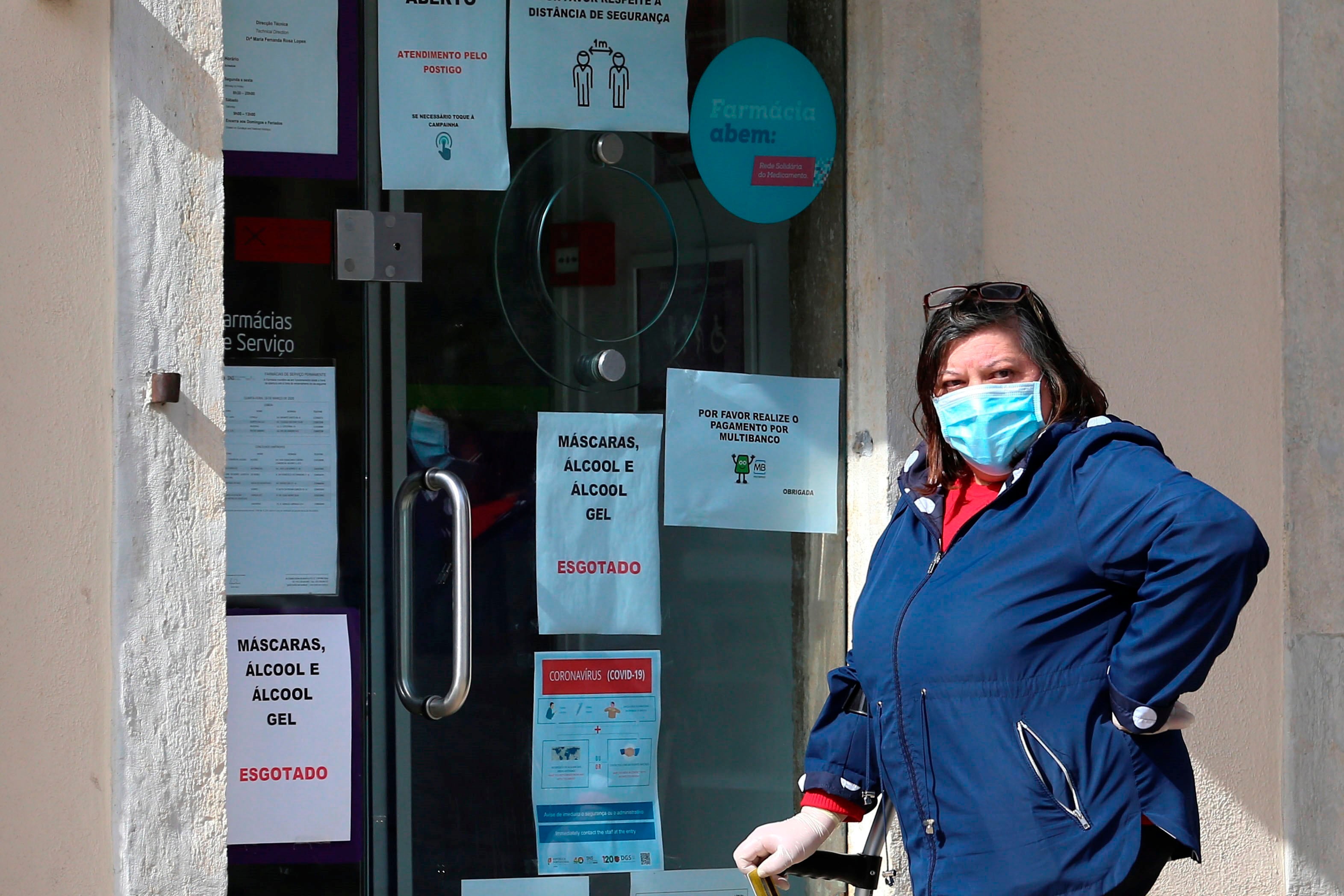 Una señora hace cola frente a una farmacia en Lisboa.