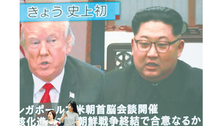 En Tokio, dos personas pasan delante de una pantalla gigante que transmitía en vivo la cumbre de anteayer.