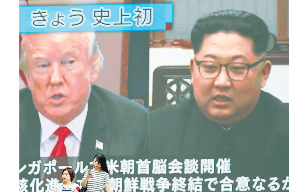 En Tokio, dos personas pasan delante de una pantalla gigante que transmitía en vivo la cumbre de anteayer.