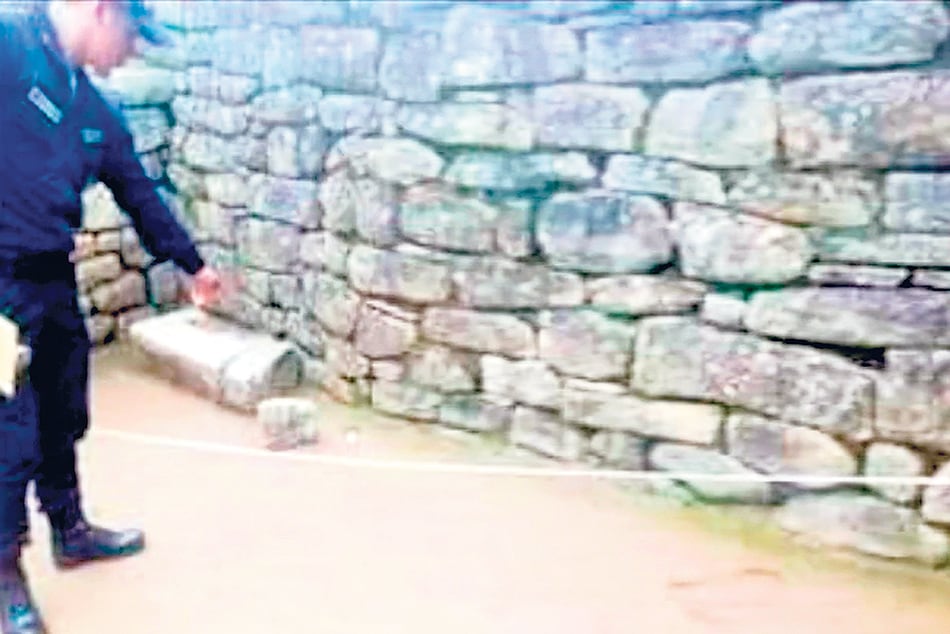 El policía peruano señala la rotura en el piso del Templo del Sol.