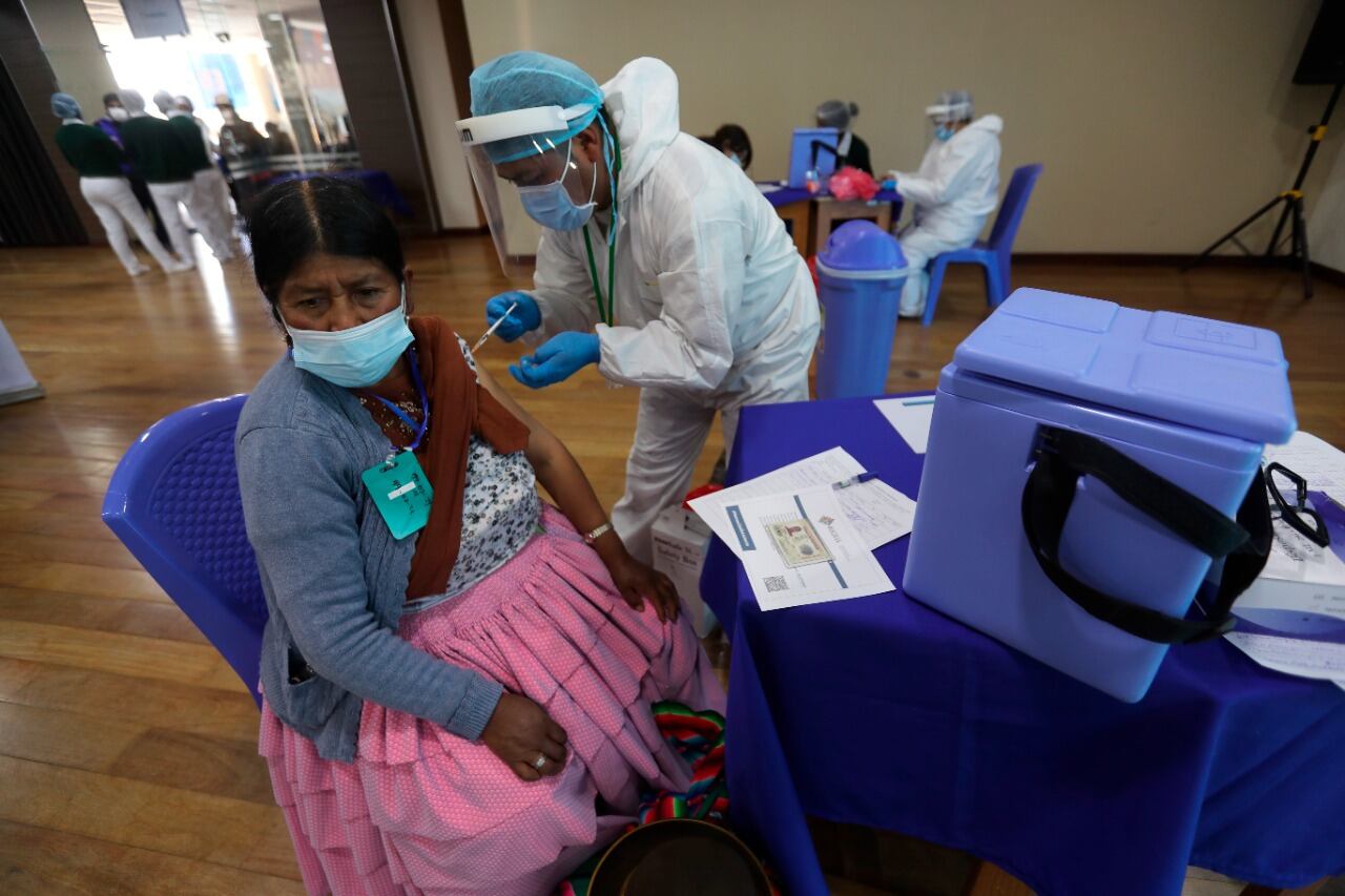Un funcionario de salud vacuna a una persona en un punto de vacunación masiva contra la covid-19 en Bolivia