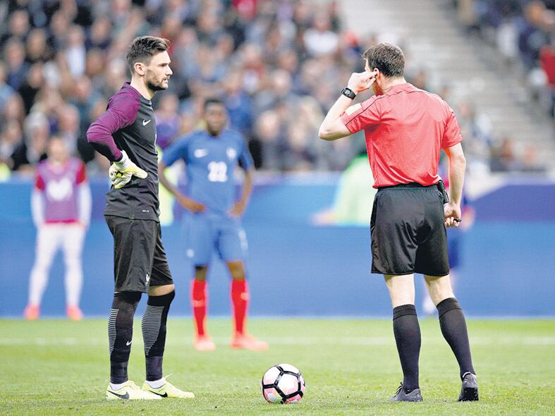 El árbitro de Francia-España escucha la resolución del juez de video.