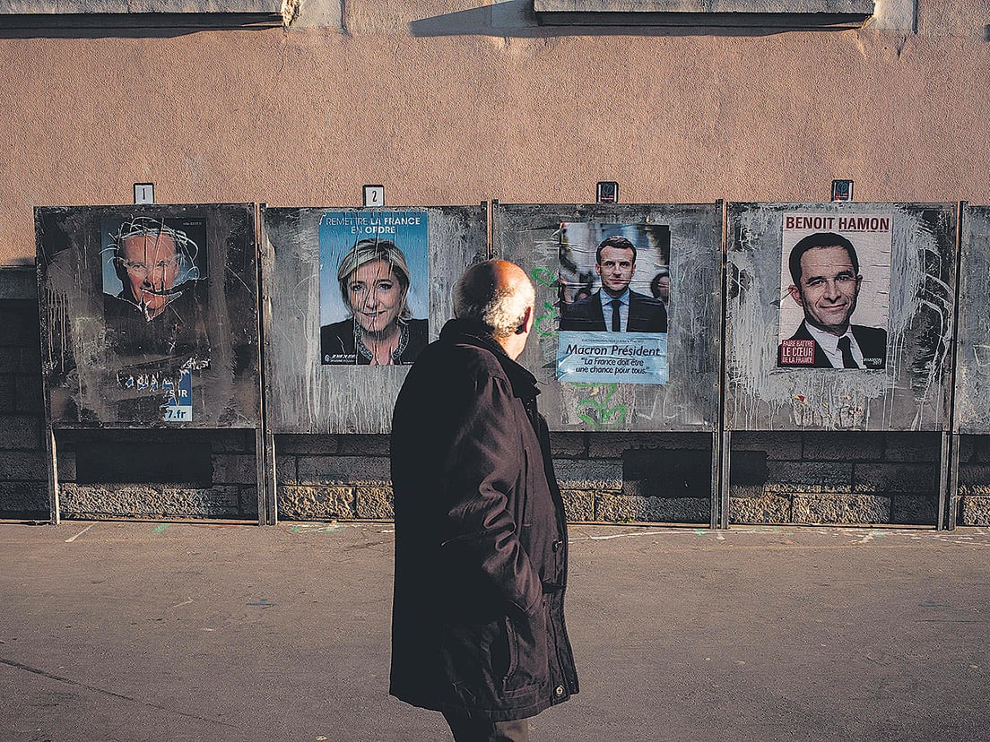 Un hombre pasa frente a unos afiches de campaña de los principales candidatos en Lyon horas antes del voto.
