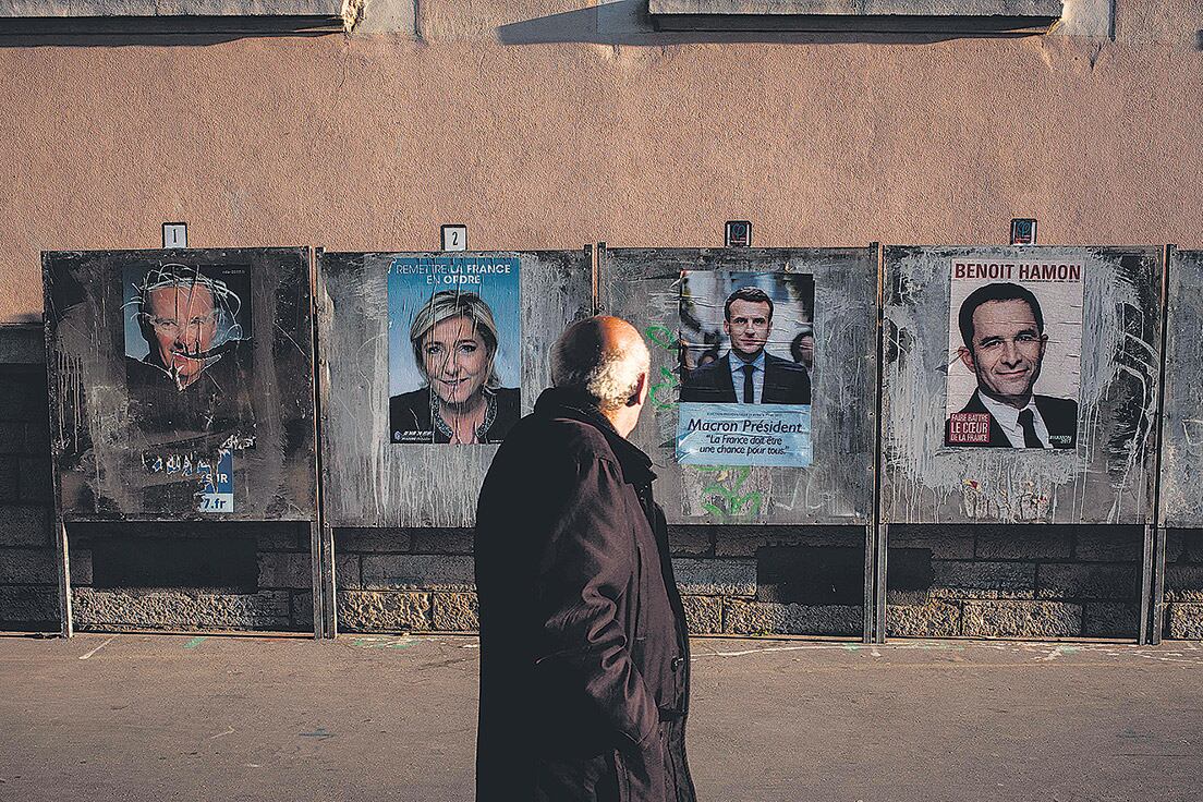 Un hombre pasa frente a unos afiches de campaña de los principales candidatos en Lyon horas antes del voto.