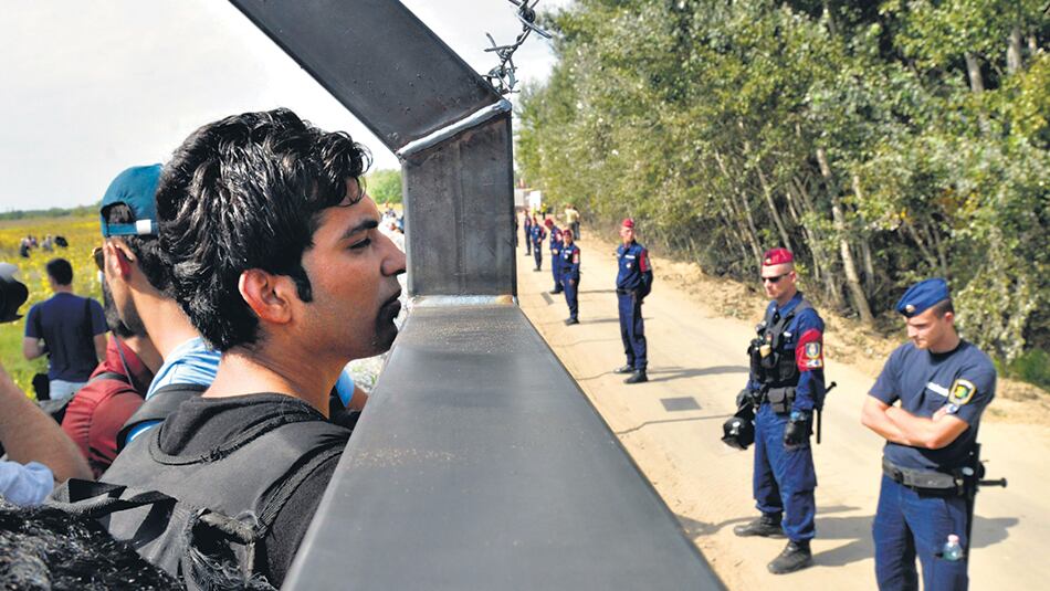 Migrantes de Africa y Medio Oriente miran desde Serbia hacia Hungría.