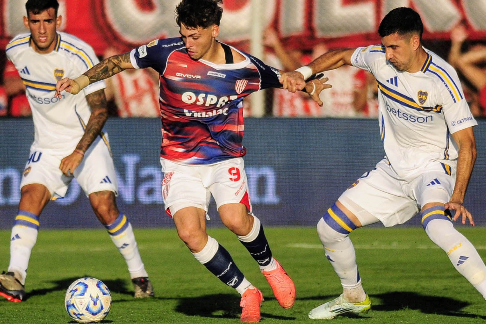 El pibe Domina maniobra entre Di Lollo y Battaglia.