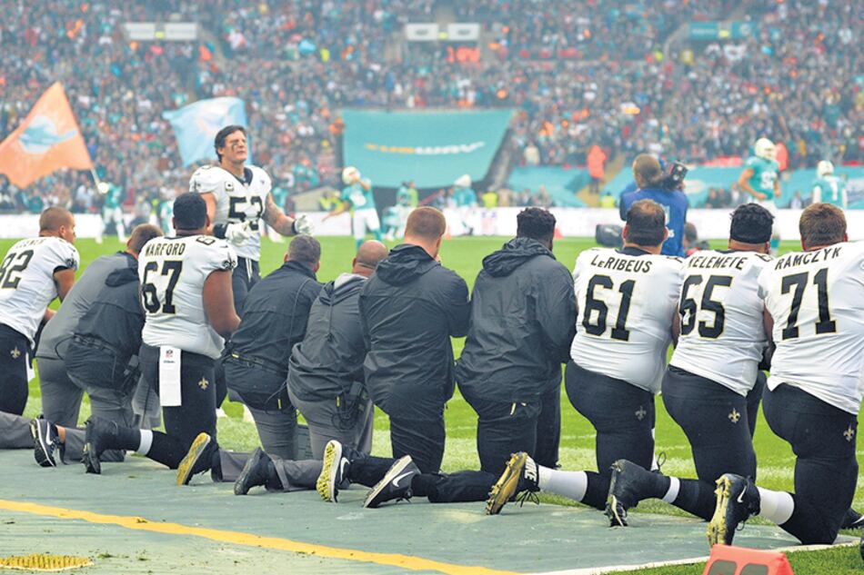 Deportistas de la NFL se arrodillan en el campo de juego durante la entonación del himno.