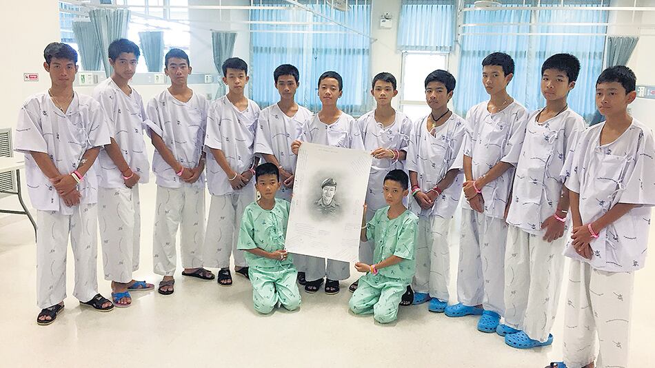 Los 13 jóvenes tailandeses, vestidos con sus batas, en el hospital de Chiang Rai, en un homenaje a Saman Kunan, el rescatista fallecido.