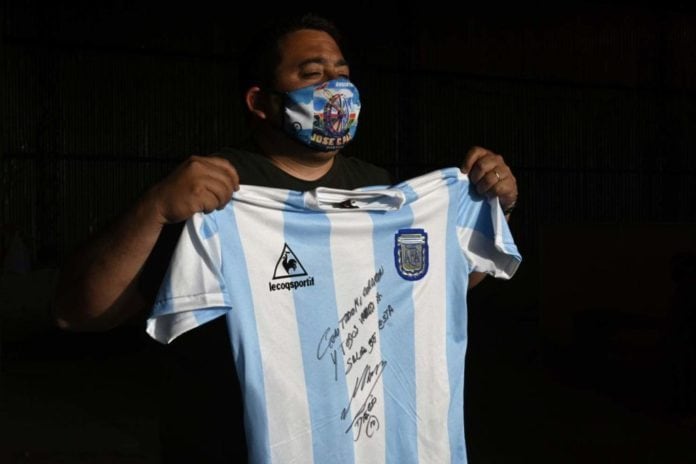 Diego Maradona y la camiseta firmada que donó para juntar fondos.