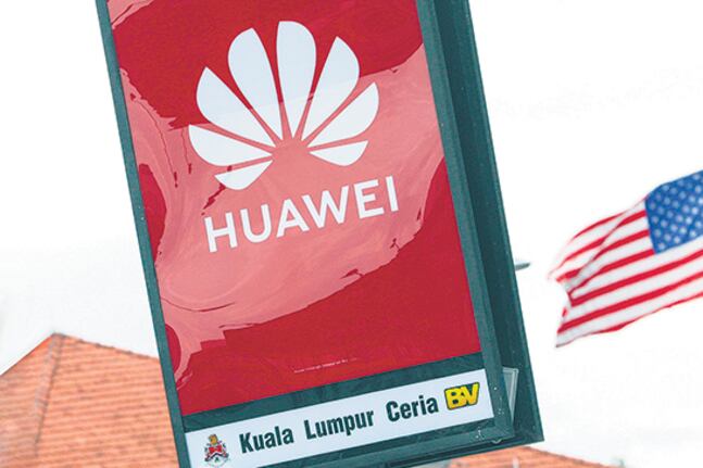 El logo de Huawei desplegado frente a la bandera estadounidense en Kuala Lumpur, Malasia.