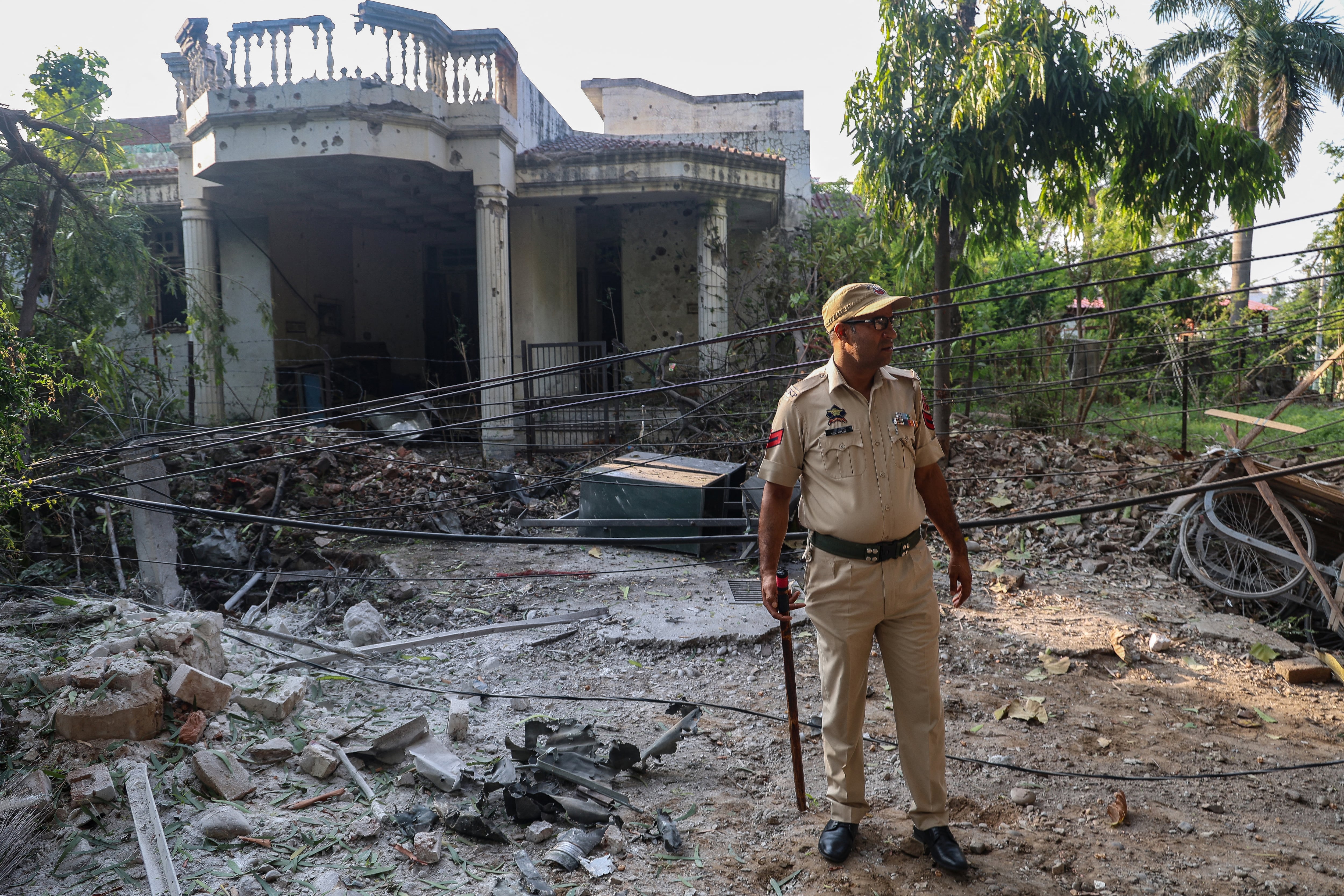Un agente de la policía india frente a una casa dañada por un bombardeo de artillería paquistaní