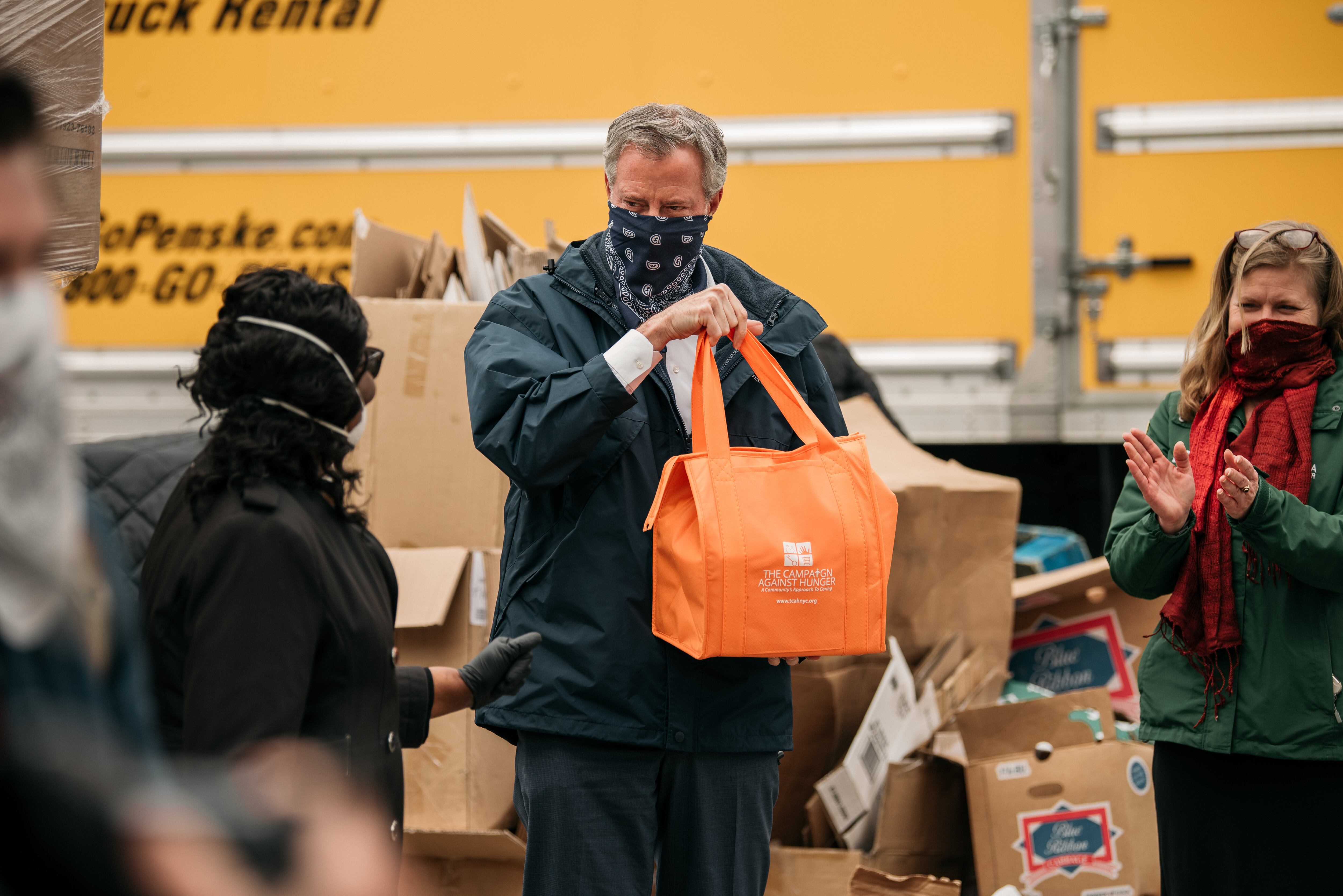 De Blasio sostiene una bolsa de comida en un refugio para personas sin techo de Brooklyn.