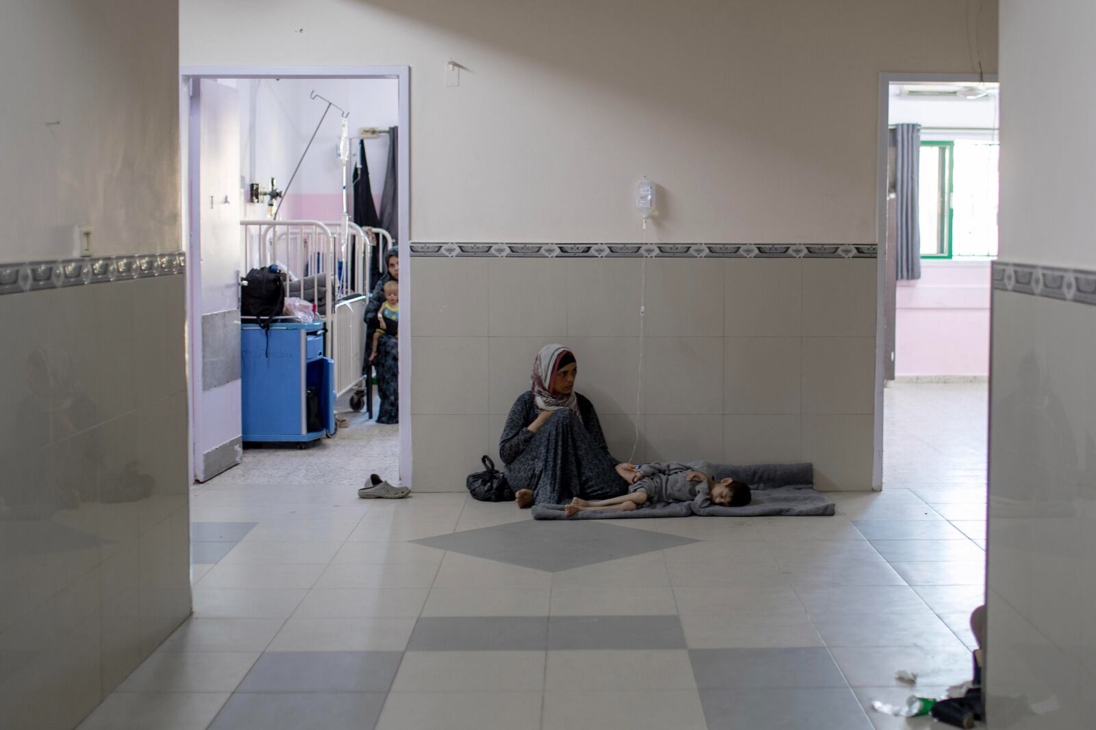 Una madre espera que su niño desnutrido sea atendido en un hospital de Khan Yunis