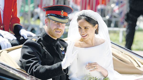 Ya casados y convertidos en los duques de Sussex (regalo de la reina Isabel), Harry y Meghan saludan desde un carruaje descubierto.