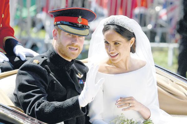 Ya casados y convertidos en los duques de Sussex (regalo de la reina Isabel), Harry y Meghan saludan desde un carruaje descubierto.