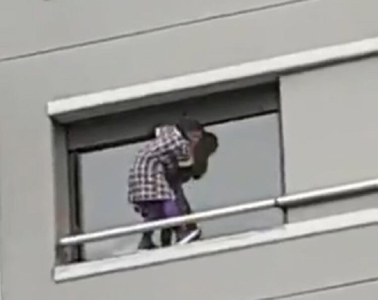 La mujer que limpia la ventana, del lado de afuera, en un sexto piso.