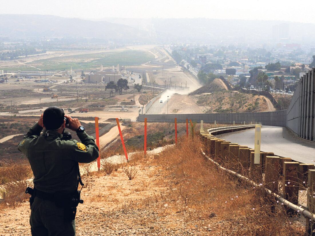 Un oficial de la Patrulla Estadounidense de Frontera vigila Tijuana con sus binoculares.