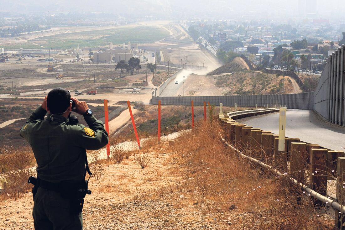 Un oficial de la Patrulla Estadounidense de Frontera vigila Tijuana con sus binoculares.