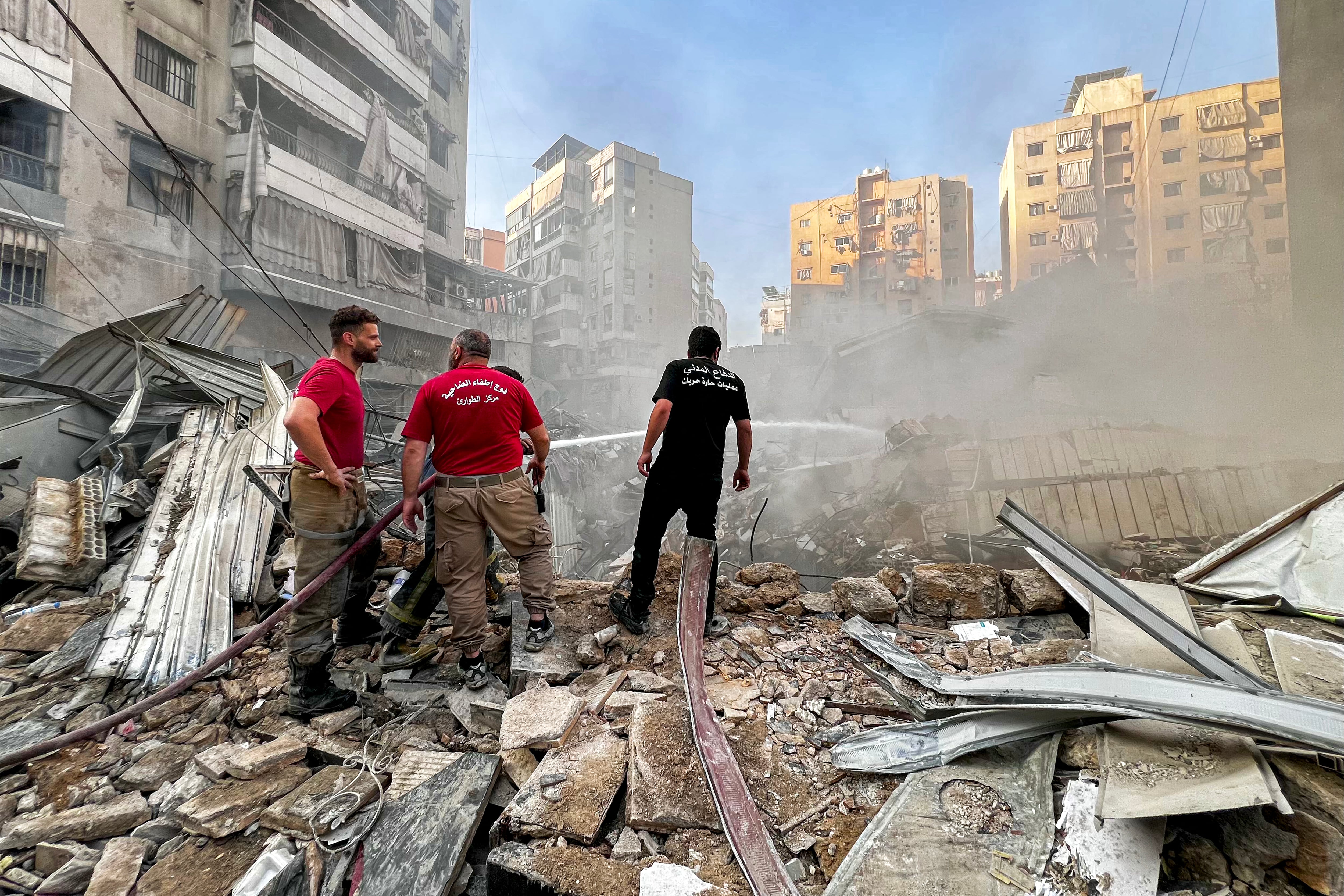 Miembros de la defensa civil libanesa y bomberos extinguen un incendio tras un ataque aéreo israelí en el barrio de Qaem