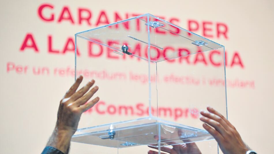 Diputados del Parlamento catalán sostienen una urna de vidrio durante la presentación.