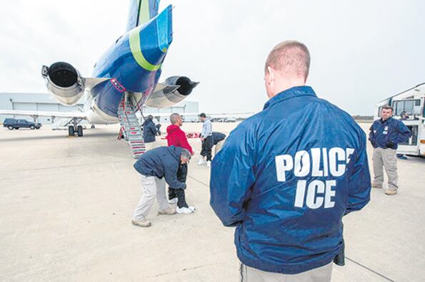 Un agente migratorio de EE.UU. controla mientras inmigrantes abordan un avión de la agencia para ser deportados.