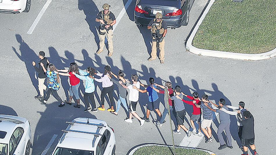 Un grupo de estudiantes evacúa la escuela secundaria de Parkland después de la masacre perpetrada por un ex alumno.