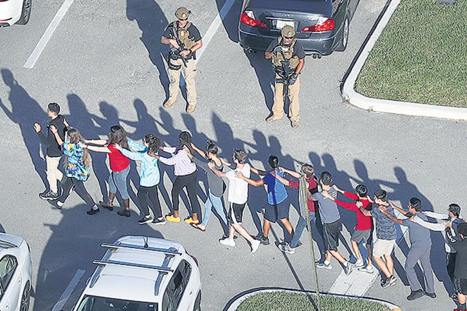 Un grupo de estudiantes evacúa la escuela secundaria de Parkland después de la masacre perpetrada por un ex alumno.