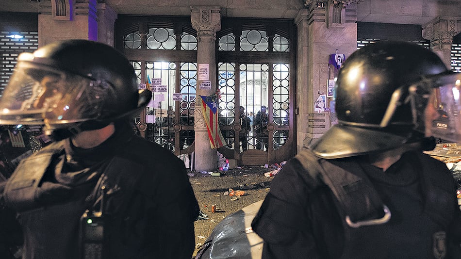 Policías catalanes observan mientras miembros de la Guardia Civil española allanan el ministerio de Economía del gobierno de Cataluña en Barcelona.