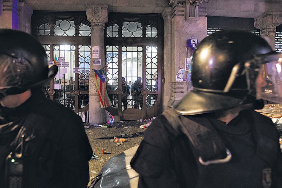 Policías catalanes observan mientras miembros de la Guardia Civil española allanan el ministerio de Economía del gobierno de Cataluña en Barcelona.