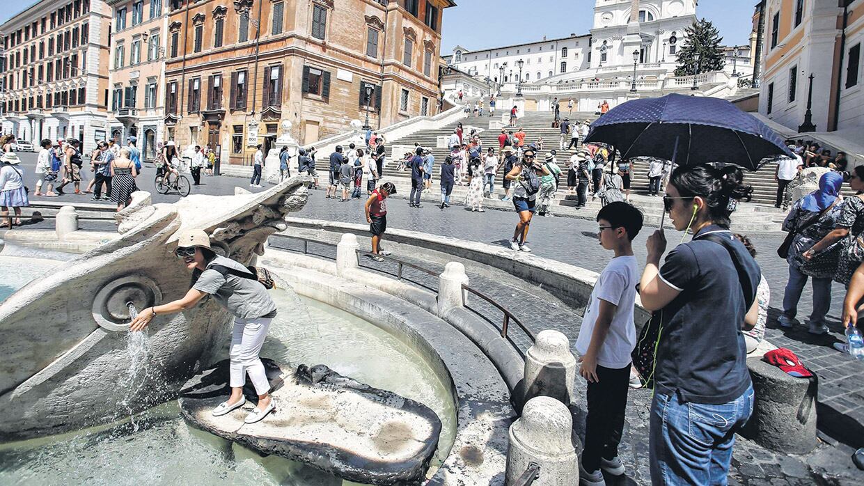 Los turistas se refrescan en la fuente Barcaccia, en la plaza España, en una Roma de calor agobiante.
