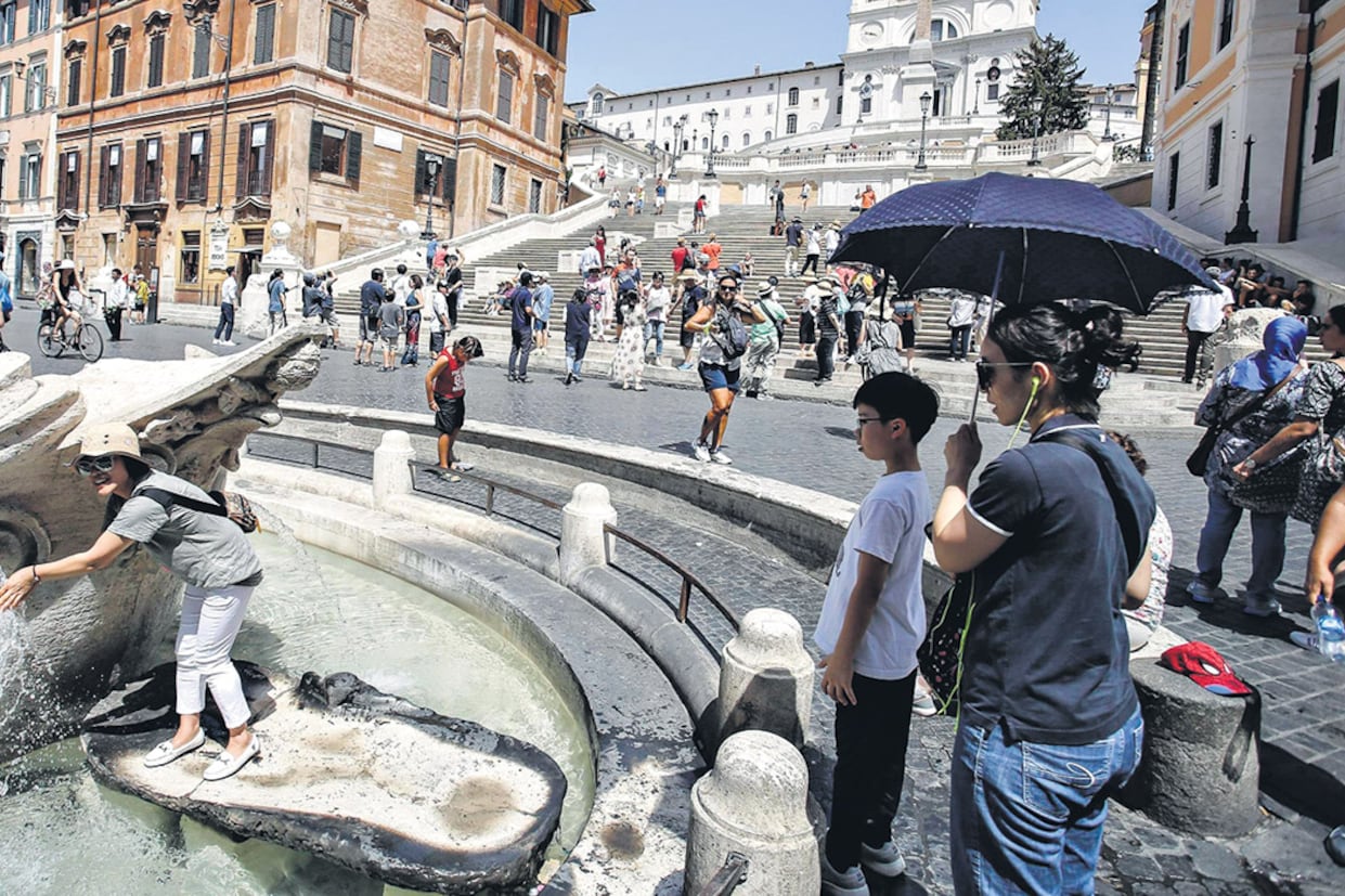 Los turistas se refrescan en la fuente Barcaccia, en la plaza España, en una Roma de calor agobiante.