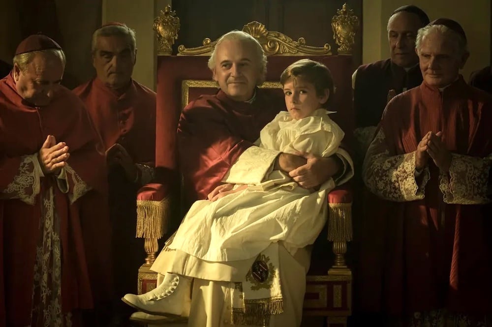 El niño Edgardo Mortara (Enea Sala) en las faldas del Papa Pio IX (Paolo Pierobon), según la visión de Bellocchio. 