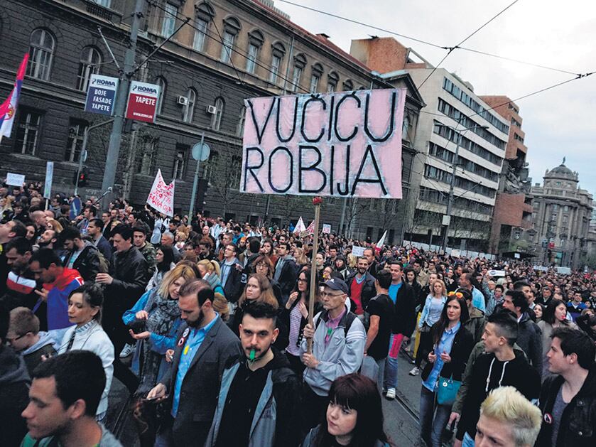Manifestantes en Belgrado, entre ellos un hombre que sostiene una pancarta pidiendo “Cárcel para Vucic”.
