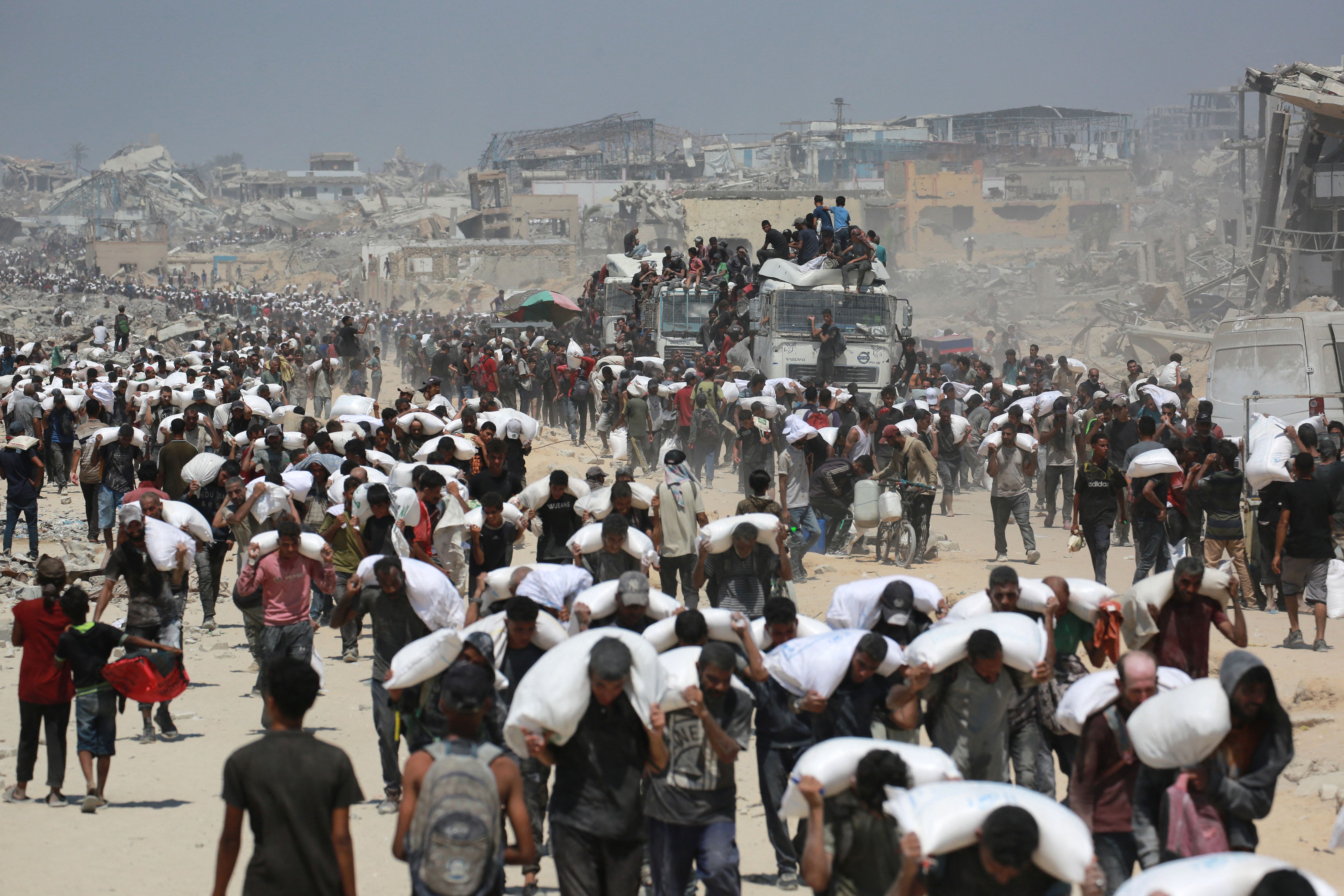 Palestinos caminan con bolsas de harina cerca de Jabalia, en el norte de la Franja de Gaza
