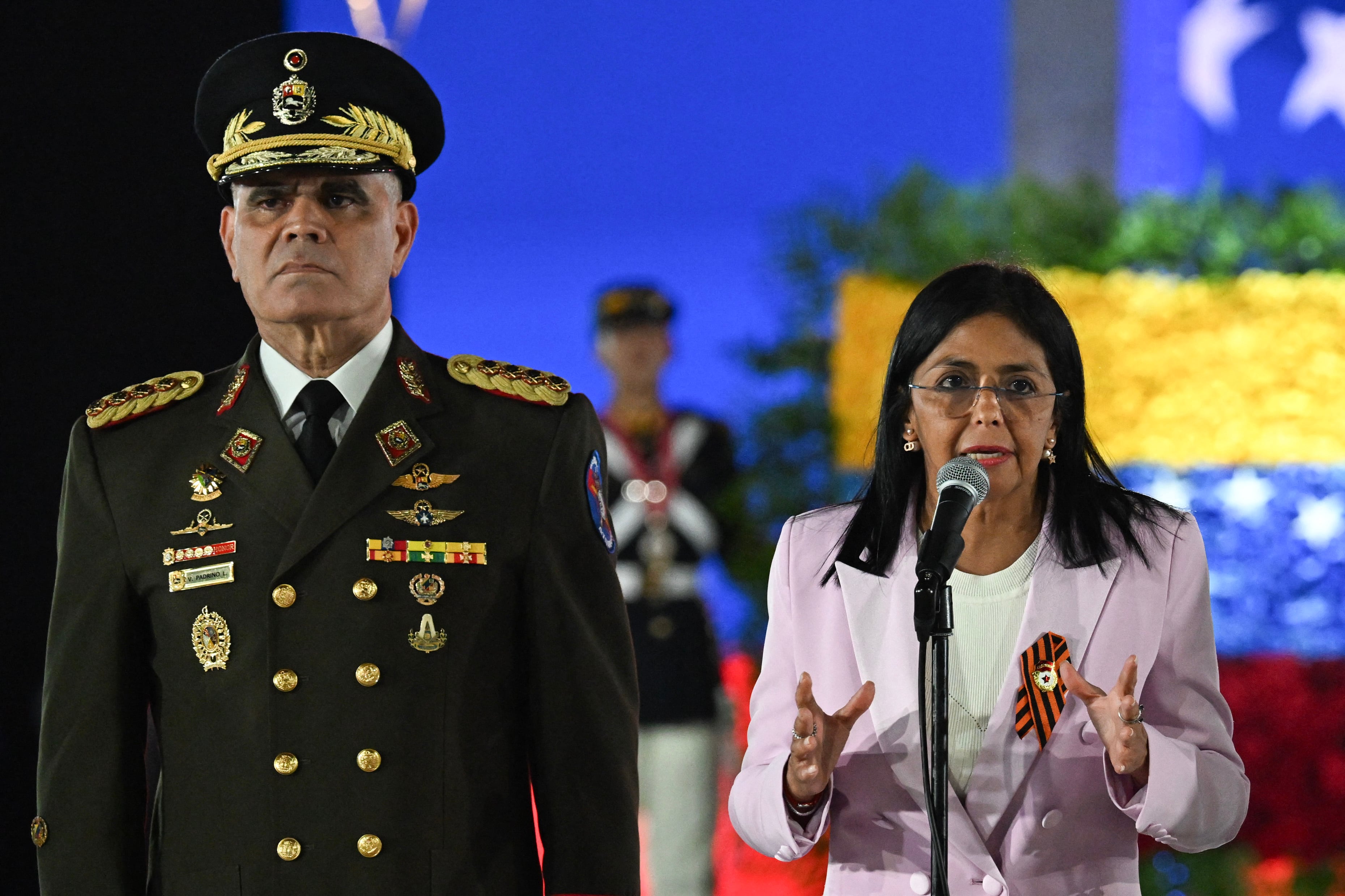(FILES) Venezuela's Vice-President Delcy Rodriguez (R) speaks next to Venezuelan Defence Minister General Vladimir Padrino Lopez during a military parade at the inauguration of Victory Square, commemorating the 80th anniversary of the Soviet Union's victory over Nazi Germany in World War Two (WWII), in Caracas on May, 13, 2025. Venezuelan President Delcy Rodriguez announced the sacking on March 17, 2026, of defence minister Vladimir Padrino Lopez, who headed the country's military for almost a decade under ousted leader Nicolas Maduro. Rodriguez, who took over after Maduro was deposed by US forces in January, thanked Lopez for his "dedication, his loyalty to the homeland, and for having served all these years as the foremost soldier in the defence of the country." (Photo by Juan BARRETO / AFP)