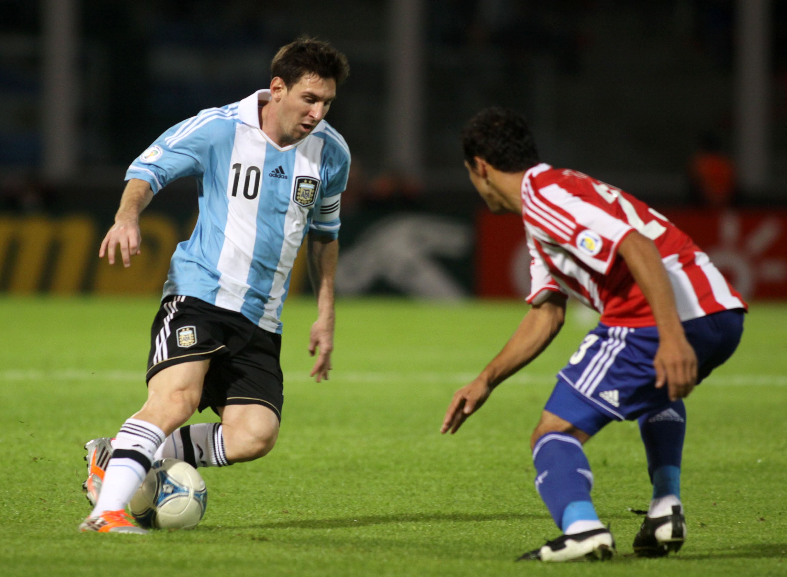 Messi va para su zurda y el rival para el otro lado. Estampa inmortal, durante el último triunfo de Argentina como local de Paraguay, en 2012