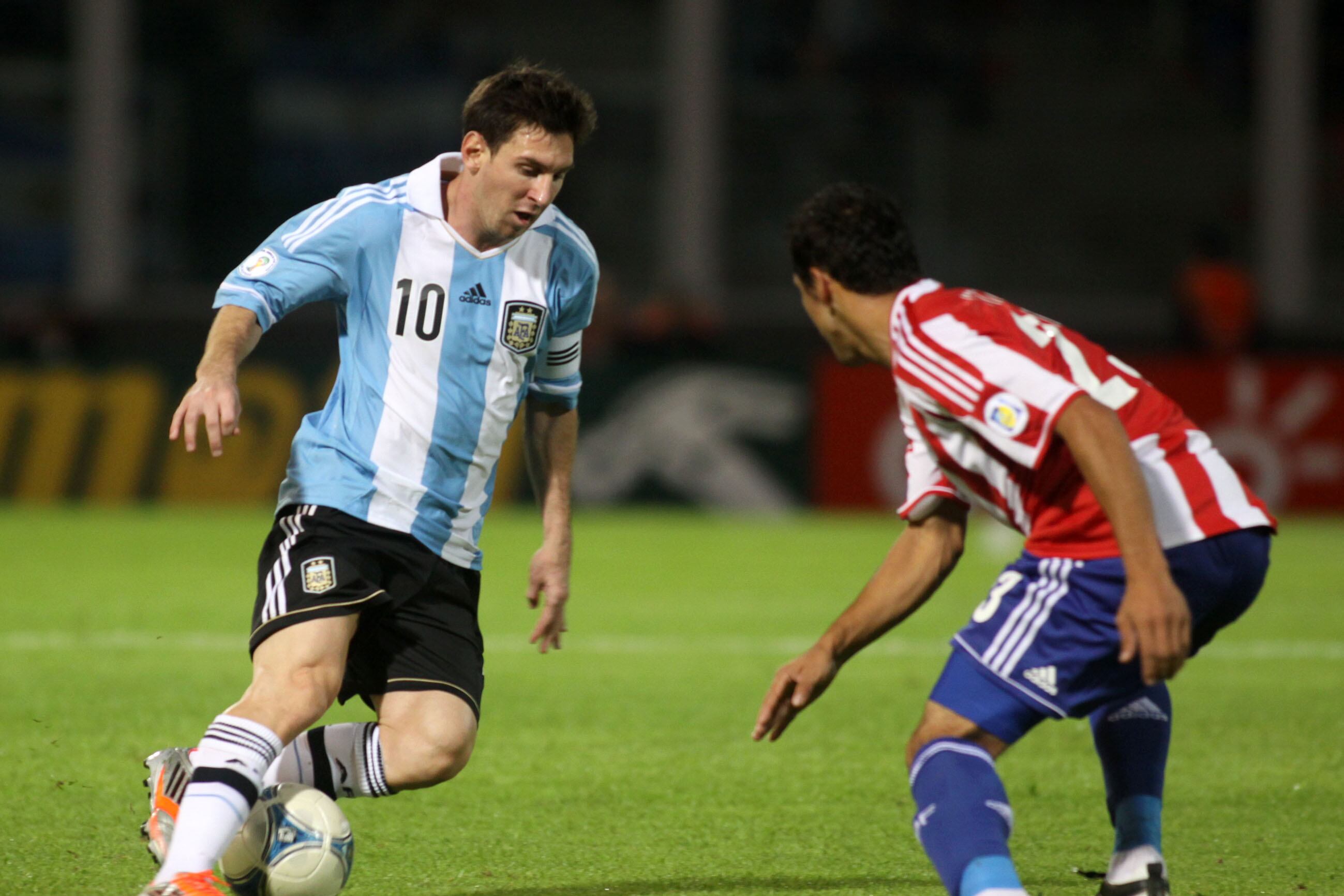 Messi va para su zurda y el rival para el otro lado. Estampa inmortal, durante el último triunfo de Argentina como local de Paraguay, en 2012