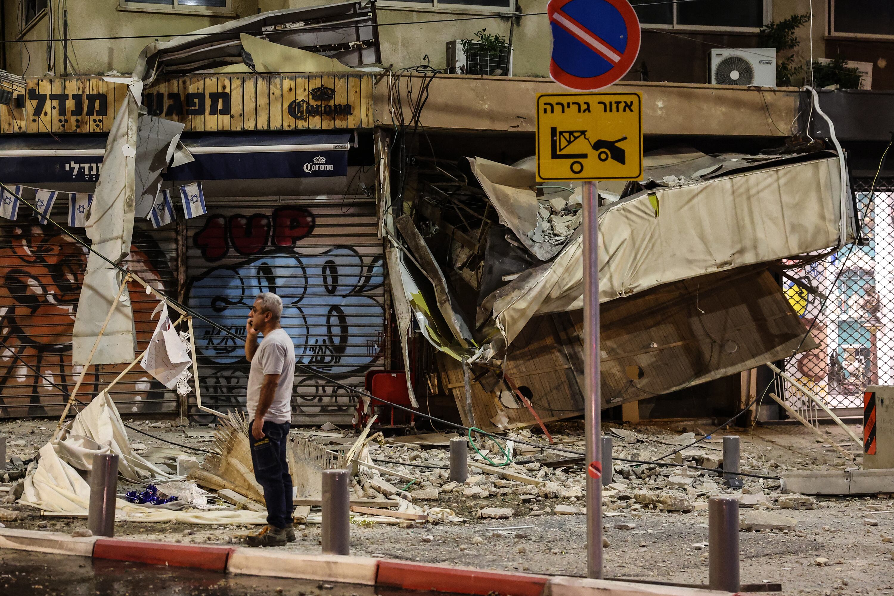 Un hombre se para frente a un negocio bombardeado en Tel Aviv.