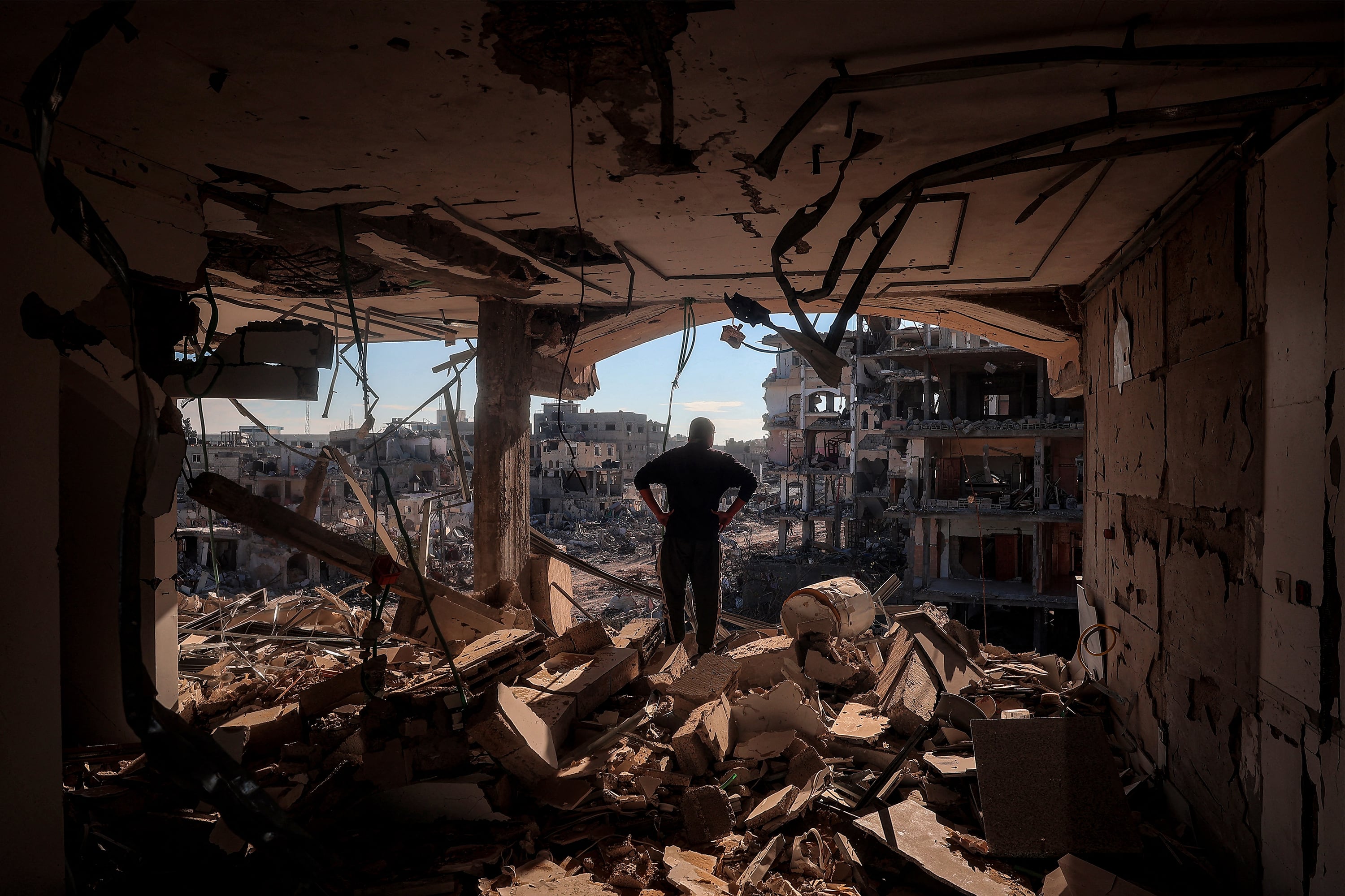 Un hombre observa la destrucción de su barrio desde un edificio sin paredes en Rafah, al sur de la Franja de Gaza