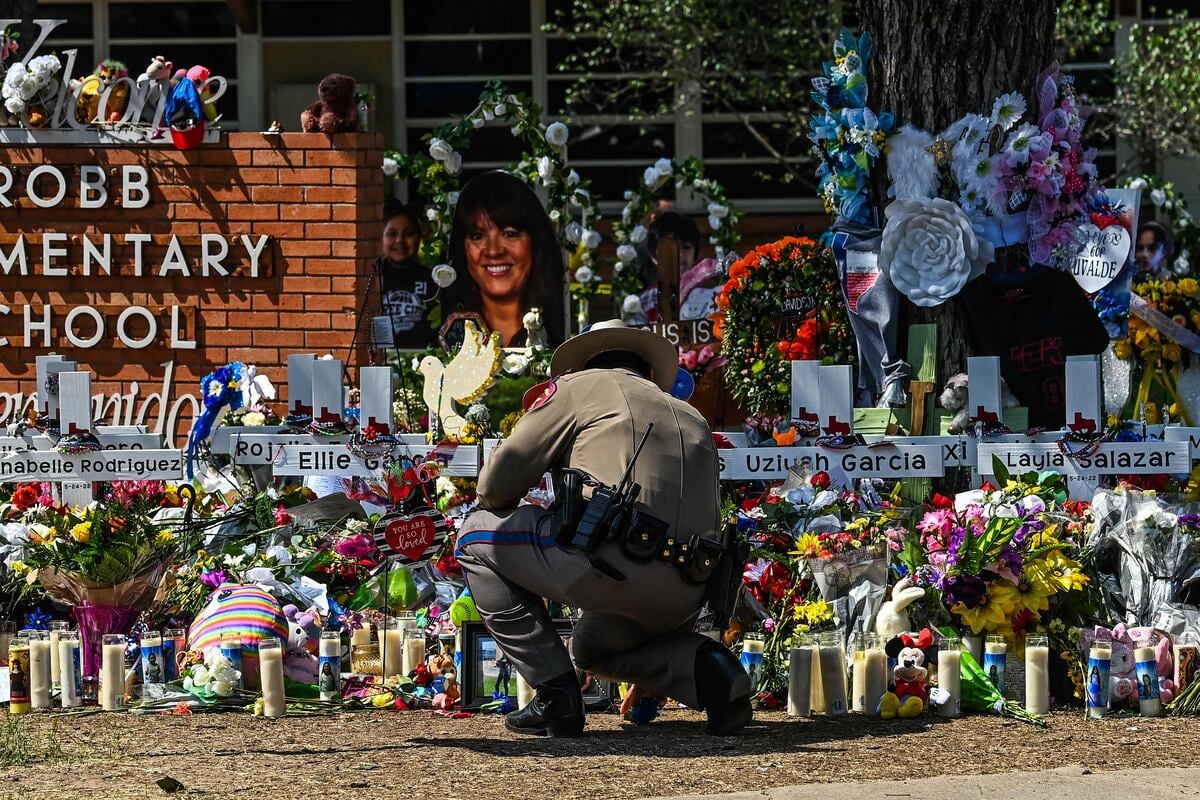 Un oficial de policía limpia el memorial improvisado en la escuela primaria Robb en Uvalde, Texas.
