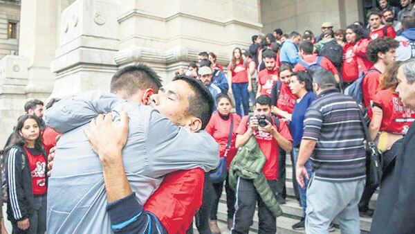 Jóvenes de La Poderosa abrazan a su fotógrafo, Roque Azcurraire, detenido ilegalmente.