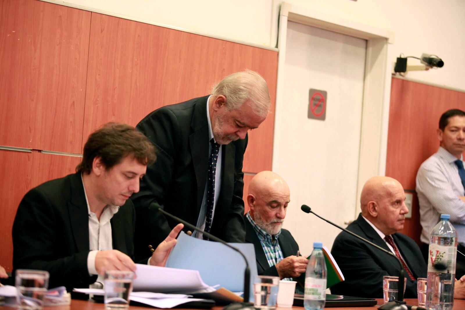 Balbuena con camisa a cuadros, barba y celular. A su lado, sentado, el co imputado y jefe policial Alejandro Sánchez. De pie, el exfiscal Álvarez Berlanda, defensor de ambos.