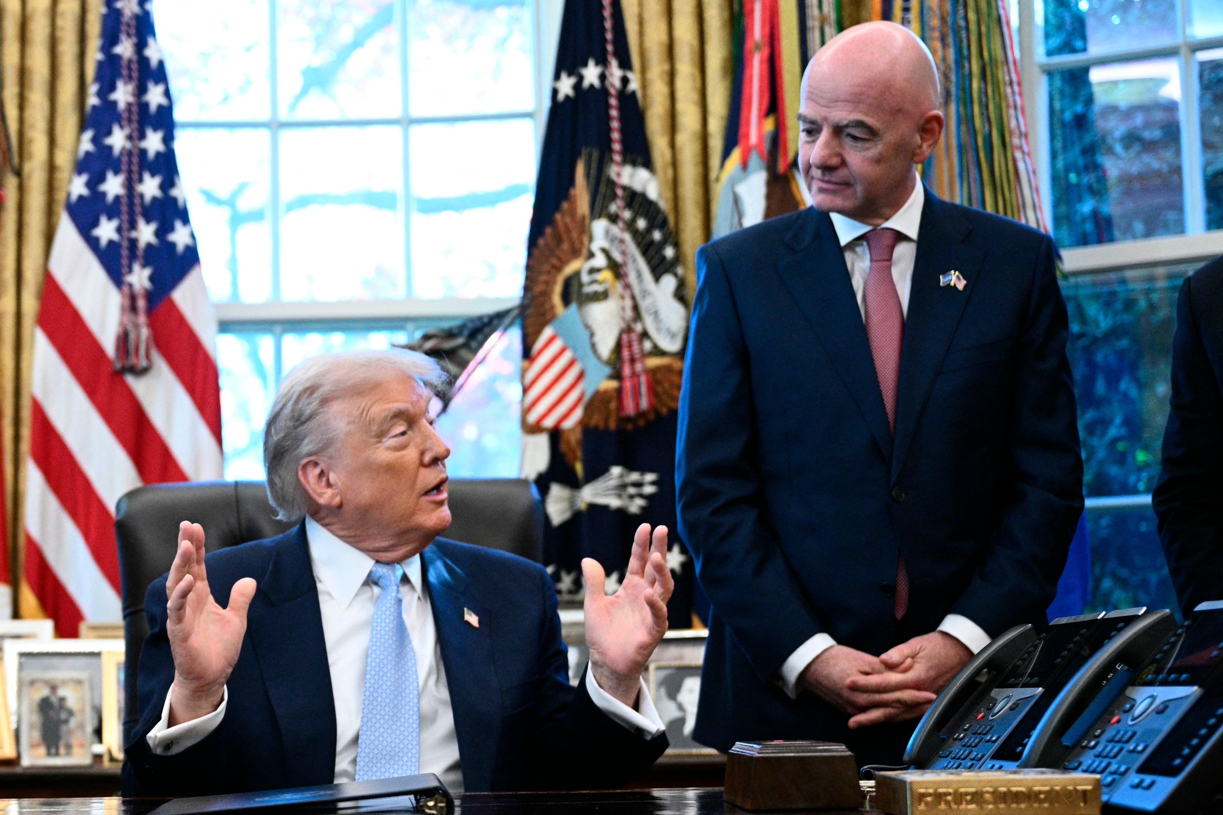 US President Donald Trump (C) speaks as FIFA president Gianni Infantino (R) and the US Secretary of Homeland Security Kristi Noem looks on during a meeting with the White House Task Force on the FIFA World Cup 2026 in the Oval Office of the White House in Washington, DC on November 17, 2025. (Photo by Brendan SMIALOWSKI / AFP)
