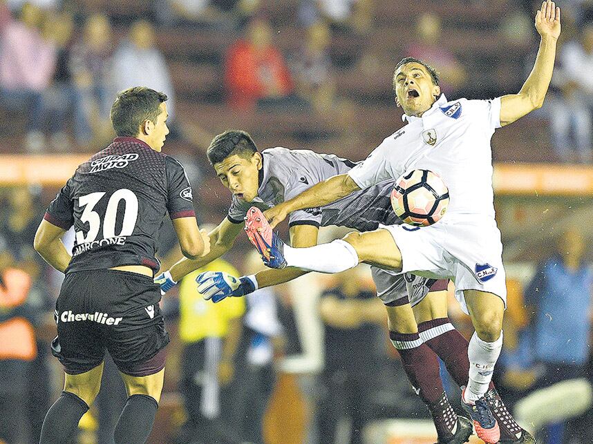 Andrada intenta frenar a Fernández, Marcone mira la pelota. 