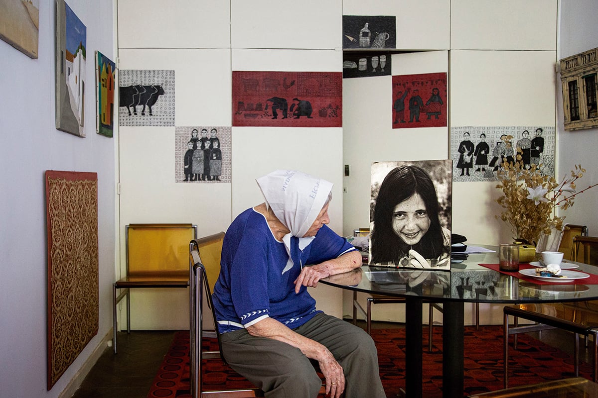 Vera Vigevani de Jarach (en el living, ante la mesa)