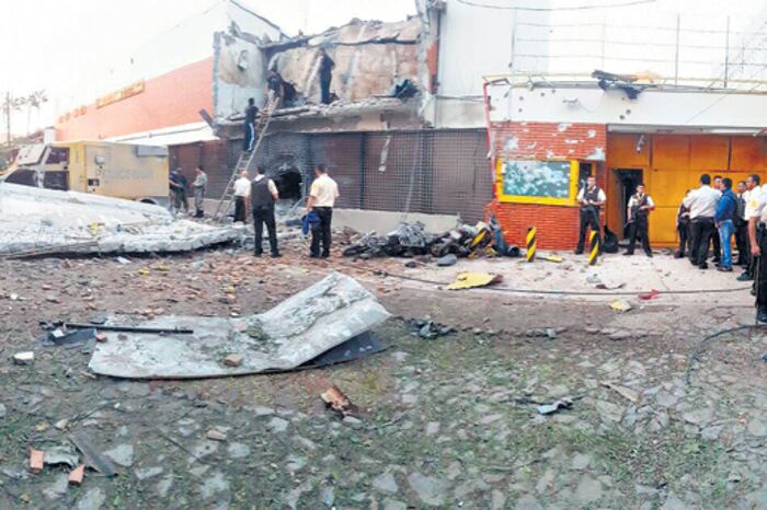La explosión hizo volar el edificio de la empresa. A la derecha, un blindado entre escombros, uno de los autos quemados y uno de los sofisticados fusiles utilizados.