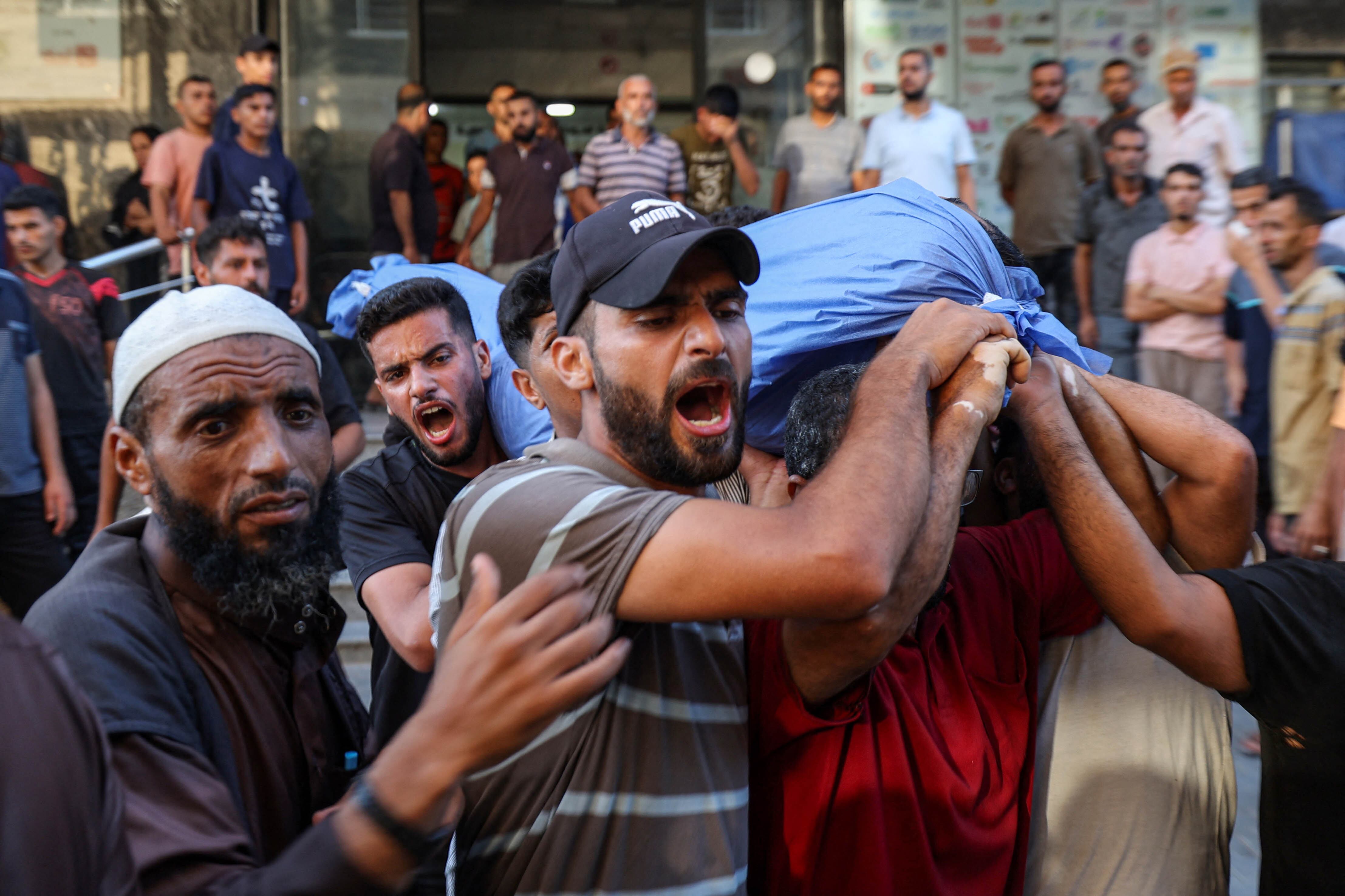 Palestinos cargan con el cadaver de una víctima de un bombardeo israelí en Gaza.